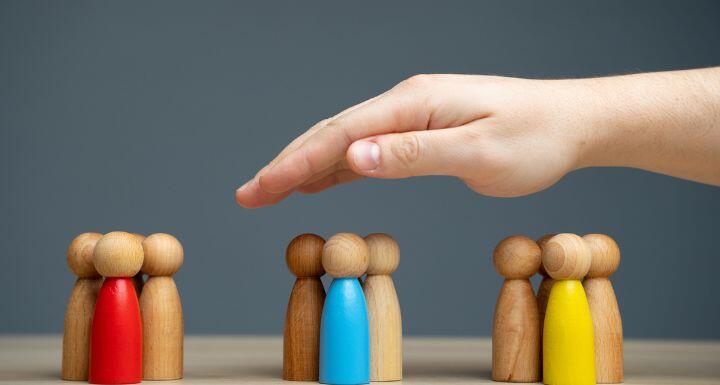 hand covering 3 groups of wooden people