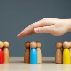 hand covering 3 groups of wooden people