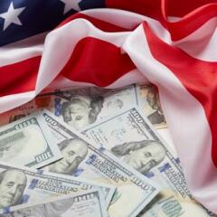 Several one hundred dollar bills arranged on top of an American flag