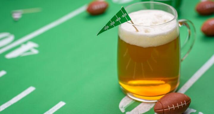 large mug of cold beer on table at big game day celebration