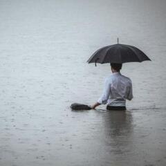 man standing in water and holding umbrella during rain