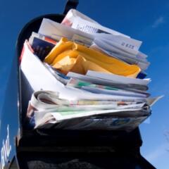 An open black residential mailbox completely overstuffed with mail