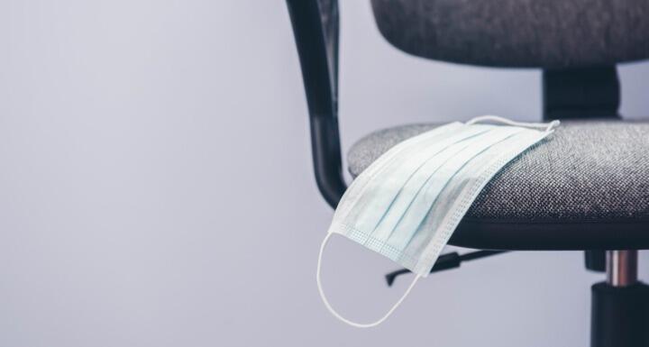 An empty office chair with a medical mask in the seat