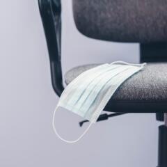 An empty office chair with a medical mask in the seat