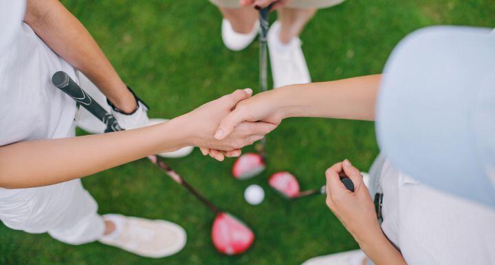 overhead view of female golf players with golf clubs shaking hands