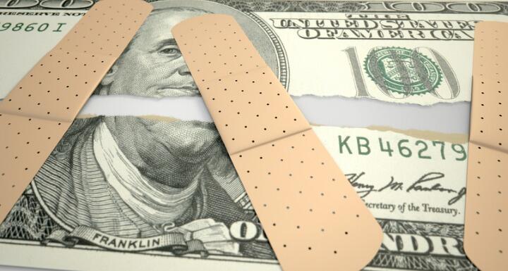 Torn money with bandaids over ripped pieces