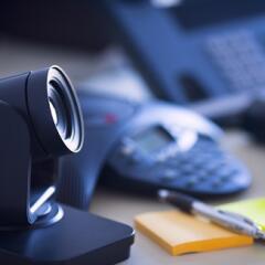 Close up of webcam sitting on a table top with a phone in the background