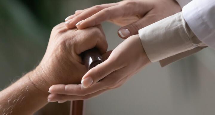 Woman caregiver hands holding elderly patient hand