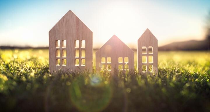 wood model house in empty field at sunset