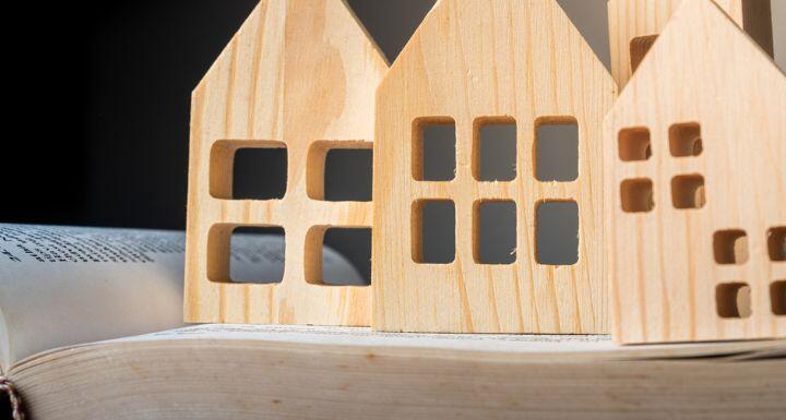 wooden house-shaped toys are arranged on top of an open book