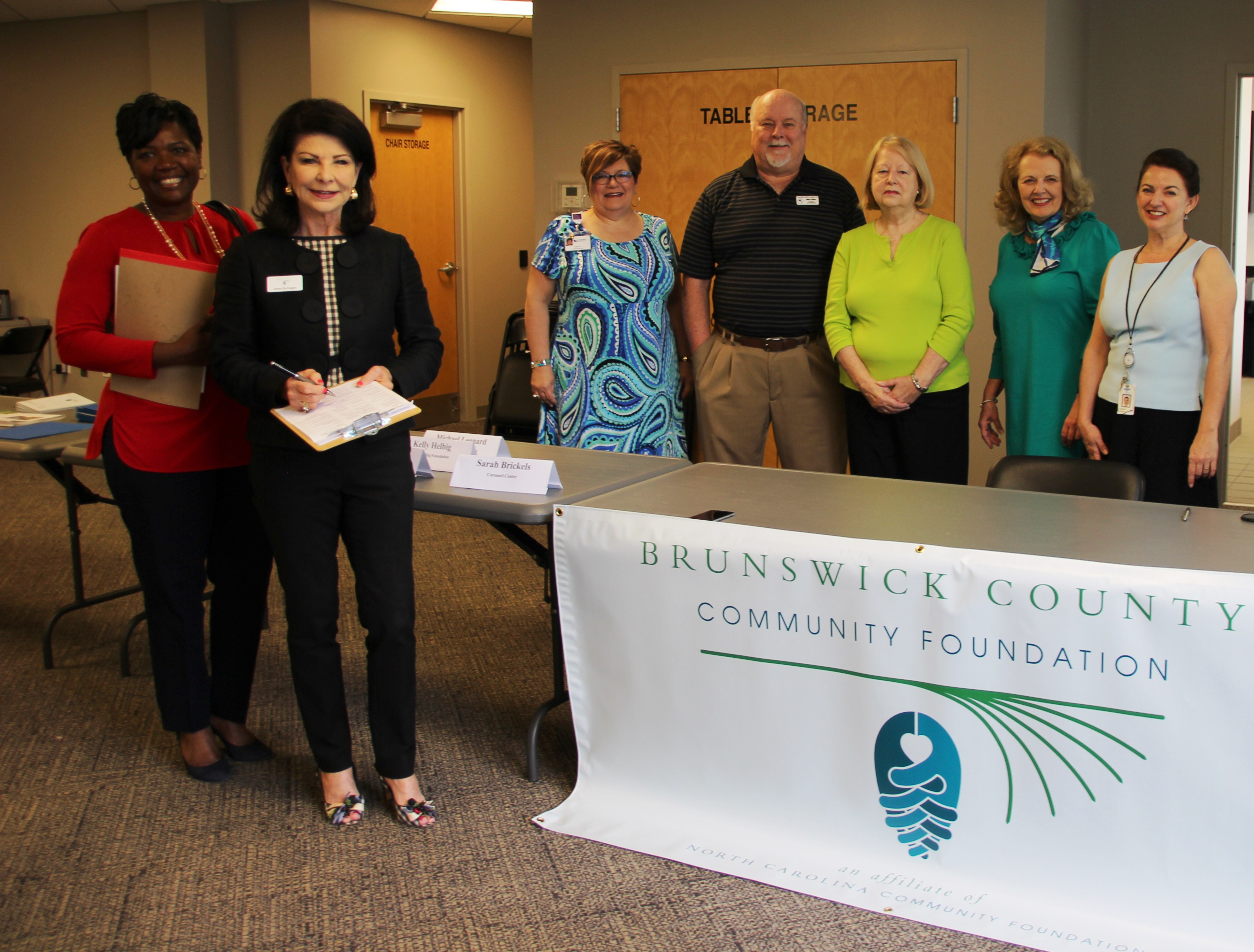 (From left to right) Linda Stanley (Novant Health Foundation), Anne Sorhagen (NCCF Regional Director), Cindy Cheatham, Mike Gildea, Jayne Matthews, Rosie Allen Ryan and Heather Holbrook (all Brunswick County Community Foundation board members) greet participants at corporate matching gifts seminar. 