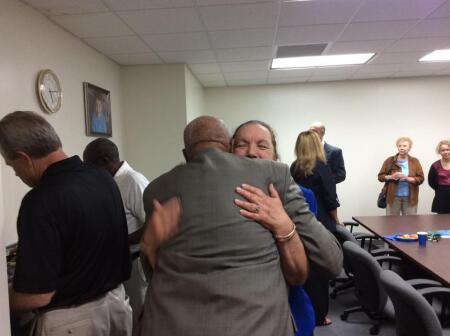 Founding Board Member and Sitting Secretary Gayle Fernandez hugging Founding Board Member John Staton.